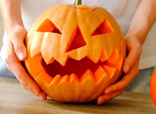 hands holding pumpkin carved for halloween