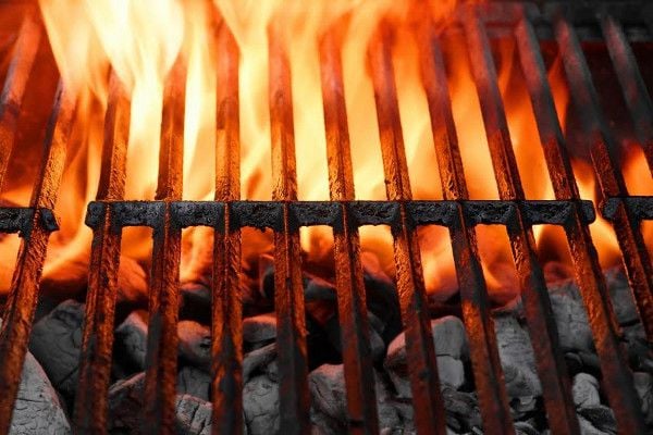 A BBQ grill with briquettes and a flame. 