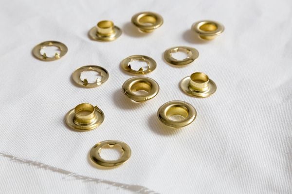 A pile of gold grommets on a white cloth. 