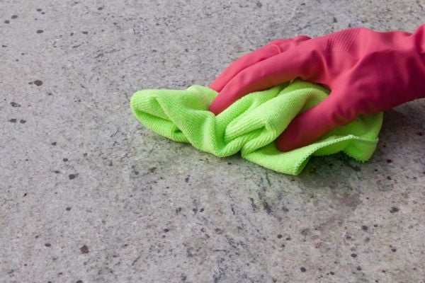 A pair of pink gloves on with a green cloth on a granite counter. 