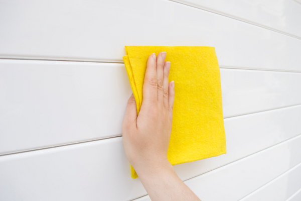 A yellow rag washing a white wall. 