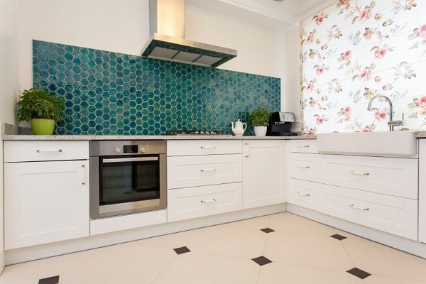 A kitchen with a turquoise backsplash. 