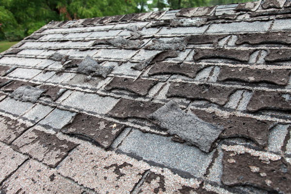 A roof with shingles in need of repair. 