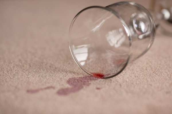 A glass of spilt wine on a carpet. 