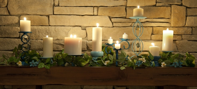 An assortment of white candles surrounded by greenery.