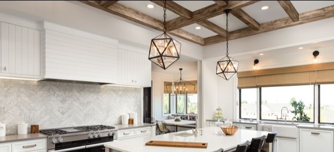 rustic kitchen with intersecting wood beams on ceiling over metal light fixtures and kitchen island