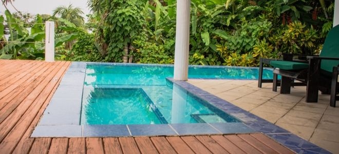 L shaped pool on wooden deck with trees