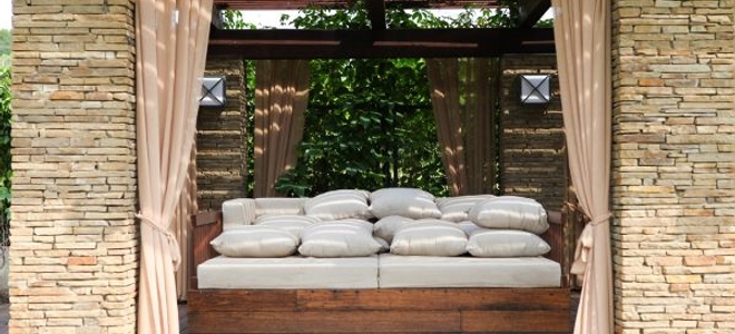 Plush built-in outdoor bed surrounded by curtains