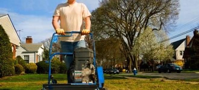 A man pushing a lawnmower toward the camera.