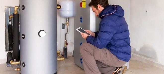 Man looking at electronic tablet while near water heater
