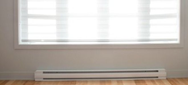 A white baseboard heater in a room with a hardwood floor.