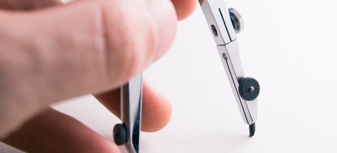 A hand on a metal drafting compass.