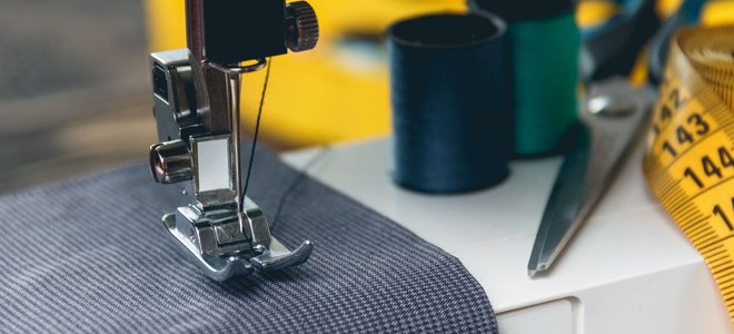 sewing machine stitching grey fabric