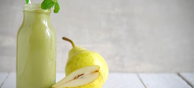 A green smoothie with pears next to it. 