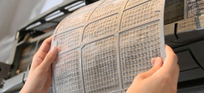A woman inspecting an air conditioner filter. 