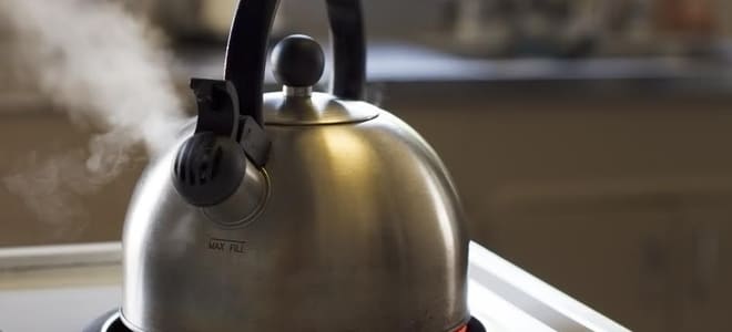 A steaming tea kettle on a stove top. 