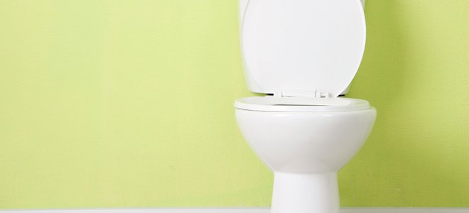 A toilet against a green wall.