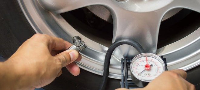 Someone testing the air pressure on a car tire.