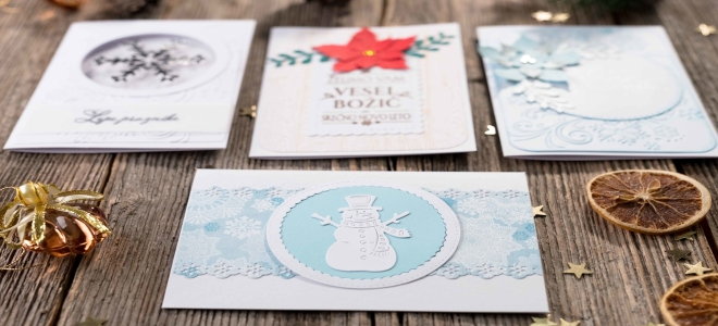 Four Christmas cards on a rustic wood table. 