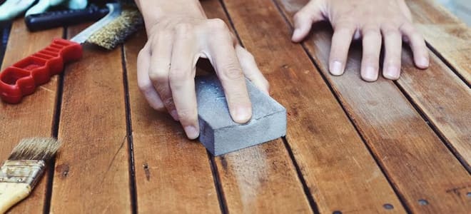 using a sanding block on wood bench slats