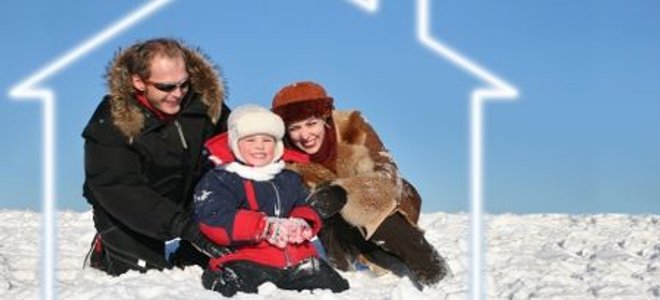 A family sits outside on the snow surrounded by the outline of a house.
