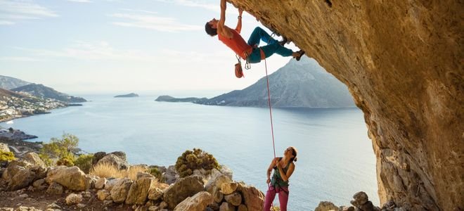 man and woman rock climbing with ropes in a beatiful coastal area