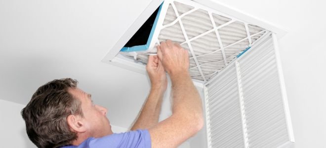 man adjusting filter in large air vent