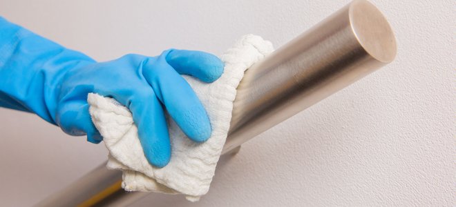gloved hand wiping a metal handrail