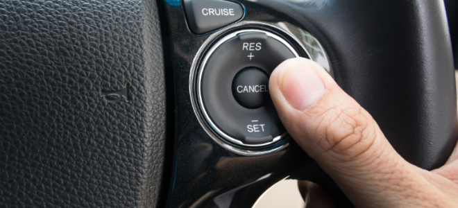 A person's finger on the cruise control button in the car