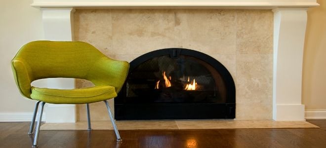 A tile fireplace with a green chair against it. 