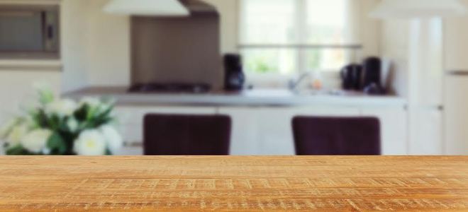 A closeup of a wood kitchen counter with a kitchen in the background.