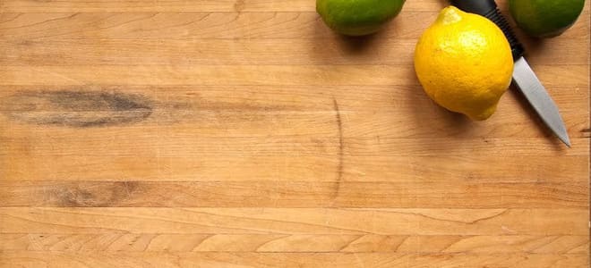 A wood countertop with a knife and citrus fruit. 