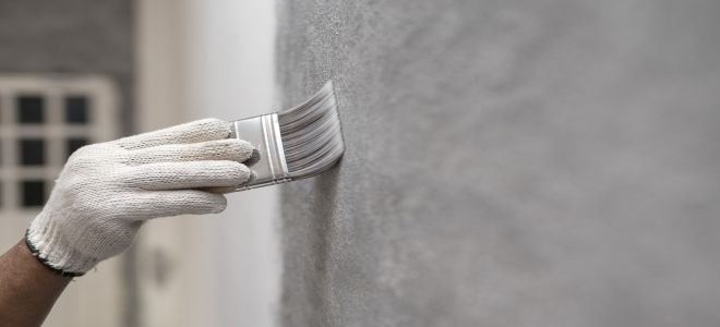 Quelqu'un qui peint un mur en béton avec un pinceau. 