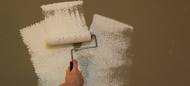 A wall with a paint roller applying primer to it. 