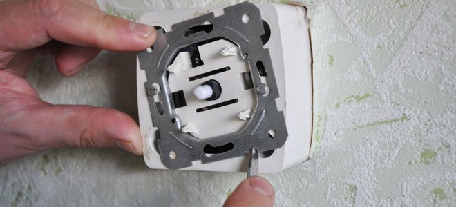 A man works on a dimmer switch.