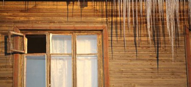 An old house with icicles and an open window.