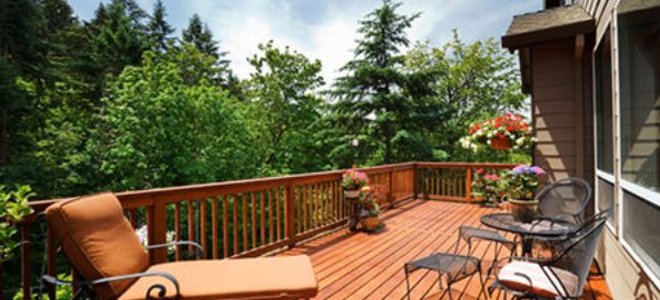 The afternoon sun shines on a back deck overlooking a slope.