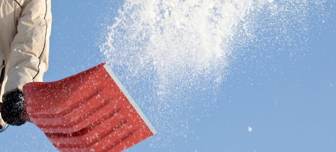 A person flinging snow into the air with a shovel. 