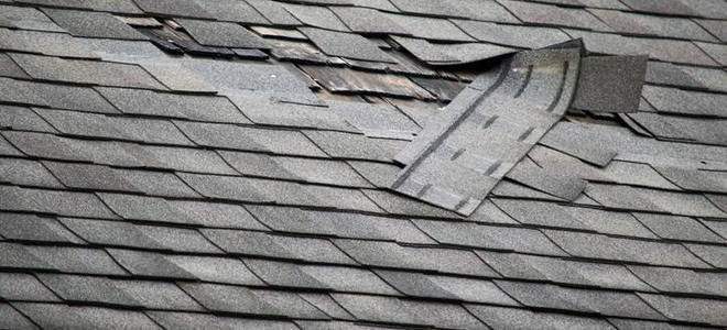 A roof with damaged shingles. 