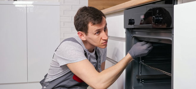person with gloves fixing inside of stove