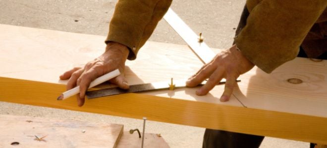 hands measuring stair stringer with square