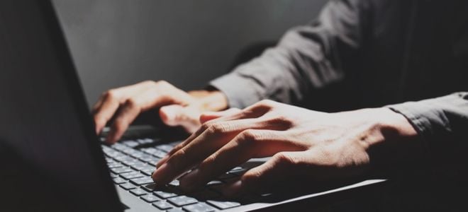 mysterious hacker hands on a laptop keyboard