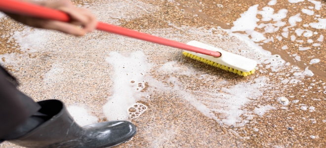 scrubbing a tile floor with broom and soapy water