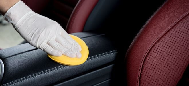 gloved hand polishing leather car interior