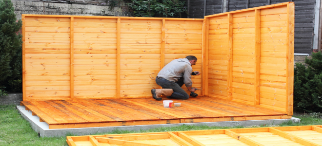 A man building a wood shed. 