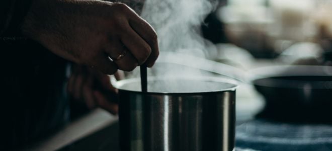 hand stirring steaming or boiling liquid in a pot