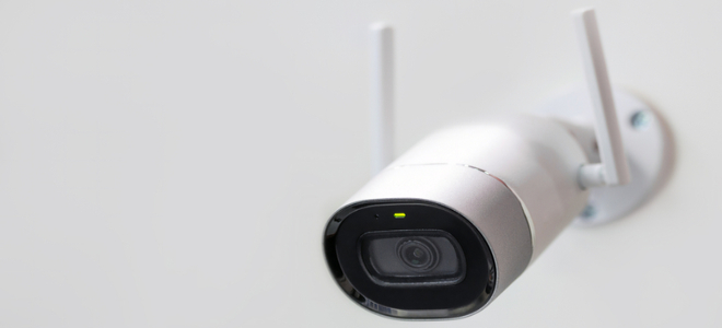 A wireless security camera on a white wall