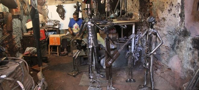 man desplaying elaborate metal statue crafts for sale
