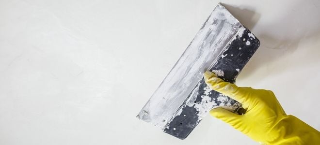 spackling a wall with a glove and flat tool