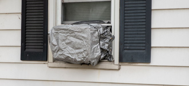 window AC unit covered with tarp